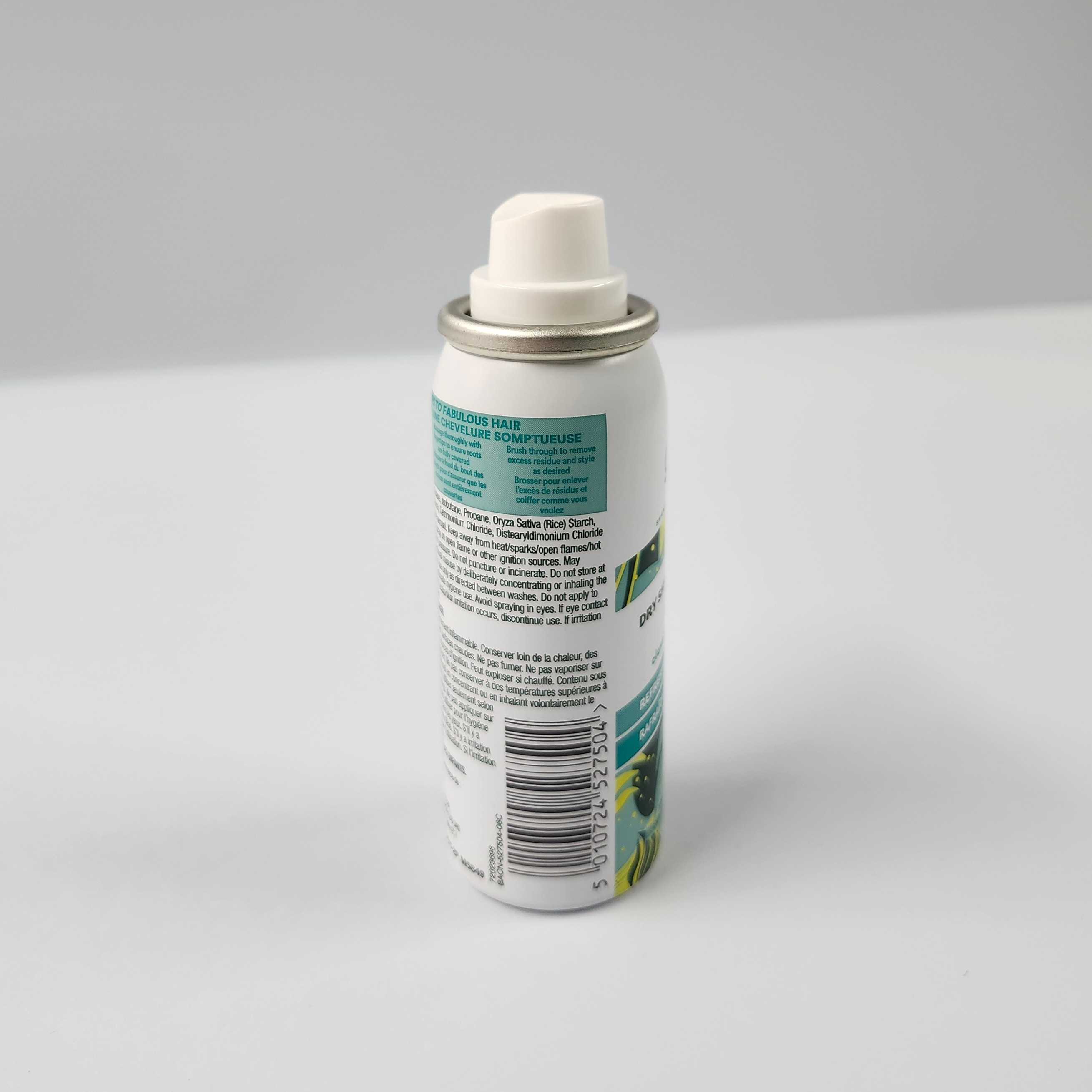 This is the side view of the mini dry shampoo bottle. It has the QR code, and there's a slight downwards cruve on the part where you press down.